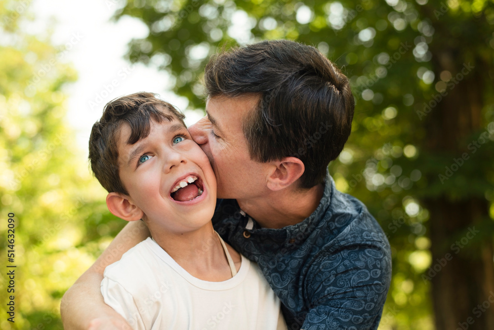 A man lovingly hugs little son, kisses him, says that he loves him very much, the son is very happy with his father and his words. Dad and son are having fun A man lovingly hugs little son, kisses him, says that he loves him very much, the son is very happy with his father and his words. Dad and son are having fun
