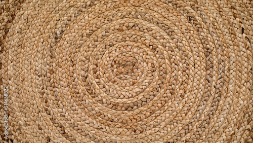 Round natural raffia rug with a spiral braided design and concentric circles that creates an ideal texture for backgrounds and graphic resources. photo