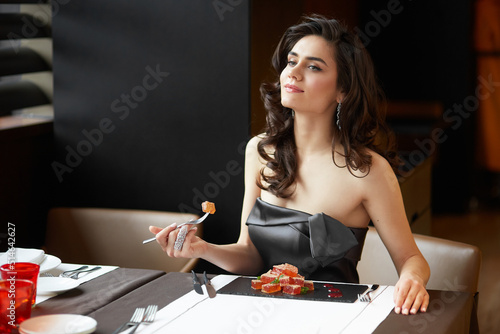 Cheerful woman in dress, serves a dessert in the restaurant, wear in a dress with bare shoulders, makeup and hairstyle.