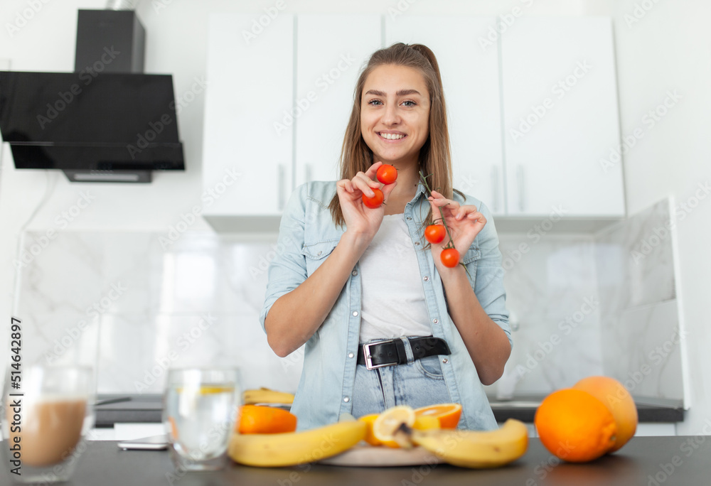 Smiling woman posing with cherry tomatoes in kitchen