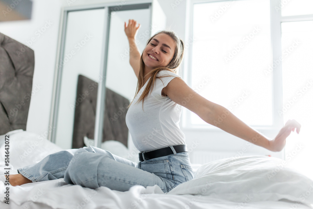 Young woman after sleep stretches her arms in a bright room Young woman after sleep stretches her arms in a bright room