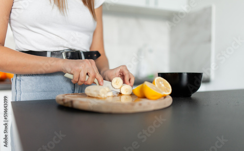 Young woman cuts fruit for salad in a modern kitchen. Healthy food concept