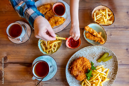 Children and man hands Picking French Fries on wood table in restaurant
