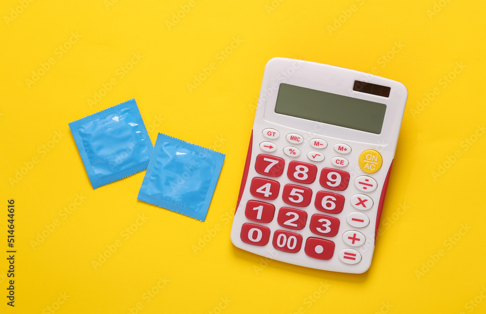 Calculator and condoms on a yellow background. Top view Calculator and condoms on a yellow background. Top view