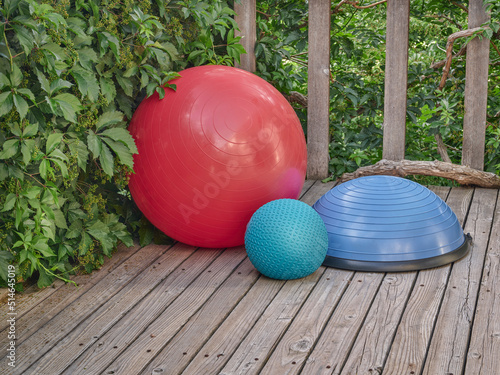 Balance Swiss, bosu and slam training balls on a wooden deck - backyard fitness concept photo