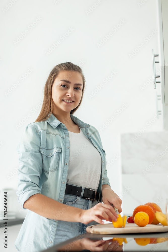 Young smiling woman cuts a lemon with a knife in the kitchen. Healthy food concept Young smiling woman cuts a lemon with a knife in the kitchen. Healthy food concept