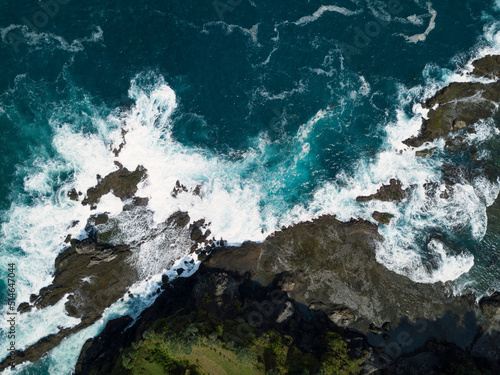 Overhead drone photo of corral rock hit by the sea wave. The sea water looks blue and made white foam. Pengilon Hill, Yogyakarta, Indonesia