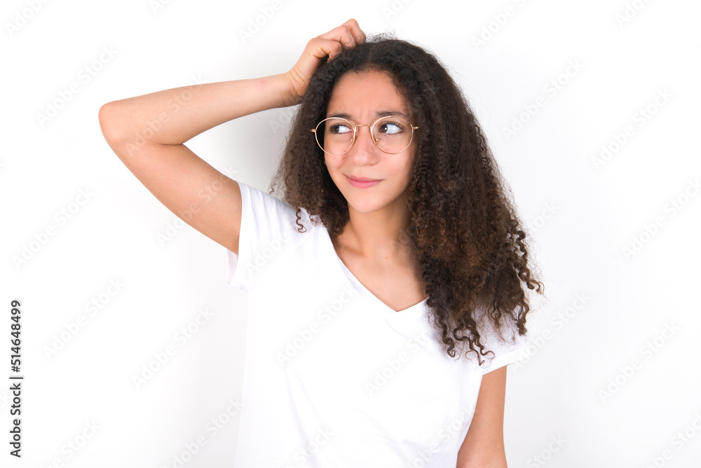 young beautiful girl with afro hairstyle wearing white t-shirt over white wall saying: Oops, what did I do? Holding hand on head with frightened and regret expression. young beautiful girl with afro hairstyle wearing white t-shirt over white wall saying: Oops, what did I do? Holding hand on head with frightened and regret expression.