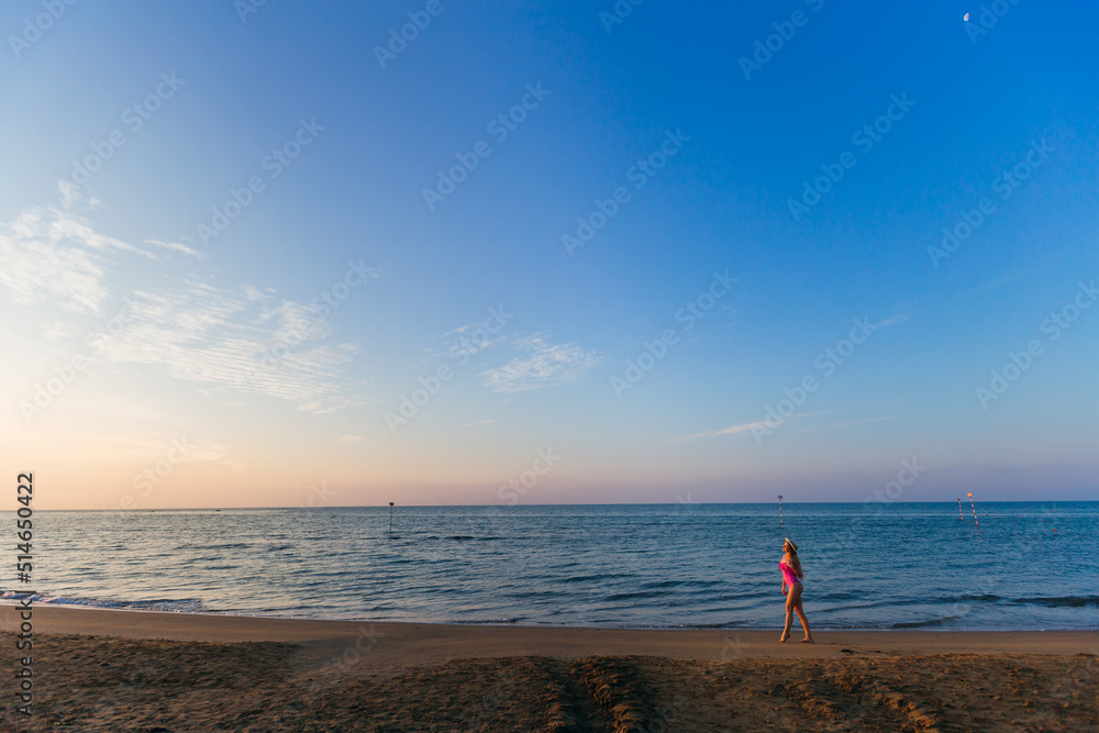 Summer woman vacations concept. girl walking on beach and admiring the sea and sunset.
