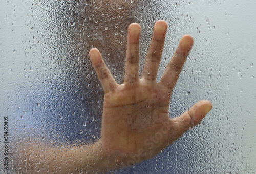 Hand of stranger on frosted glass with water drop