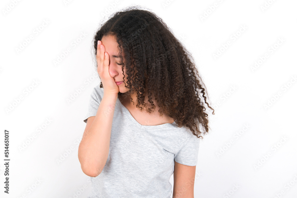 young beautiful girl with afro hairstyle wearing grey t-shirt over white wall with sad expression covering face with hands while crying. Depression concept. young beautiful girl with afro hairstyle wearing grey t-shirt over white wall with sad expression covering face with hands while crying. Depression concept.