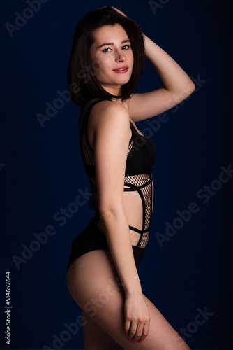 Woman posing in seductive black lingerie. Attractive beauty lady advertising underwear slim body on dark blue background free space for text © oleg_ermak