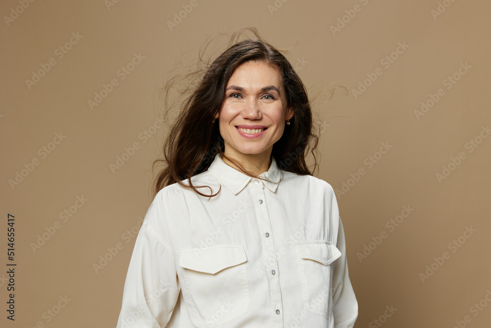 a beautiful horizontal portrait of an adult woman with black hair flowing in the wind standing in a white shirt. Studio photo with an empty space on the background a beautiful horizontal portrait of an adult woman with black hair flowing in the wind standing in a white shirt. Studio photo with an empty space on the background