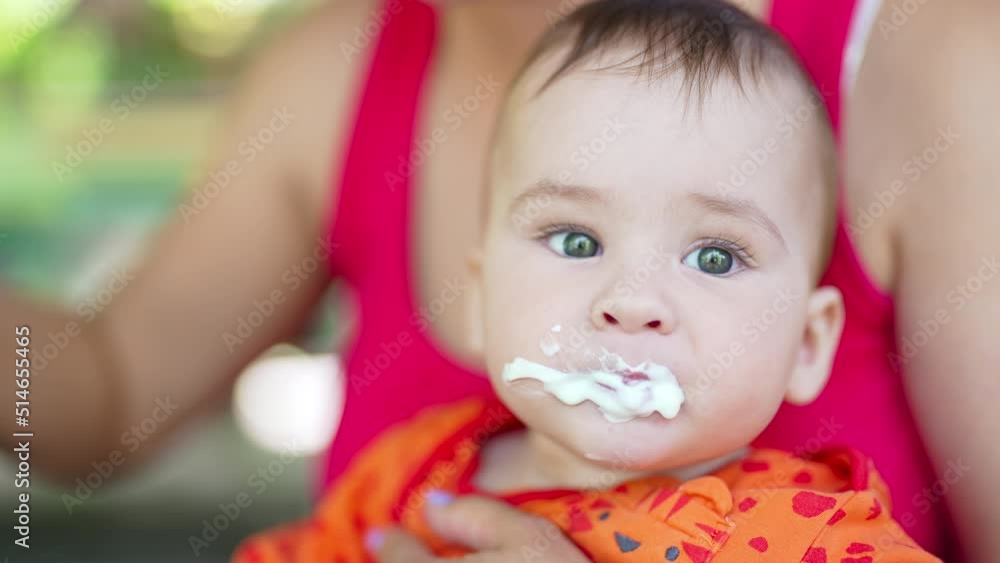 Beautiful baby murky from food he is being fed with. Mom gives a spoon to her child but he turns the head away. Close up. Beautiful baby murky from food he is being fed with. Mom gives a spoon to her child but he turns the head away. Close up.