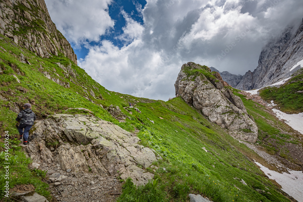 Fototapeta premium Mountain hiking Trail Road. Small mountain lake. Between Italy and Austria: near Volaia Lake Raunchkofer Mountain (Lago di Volaia Monte Rauchkofel)
