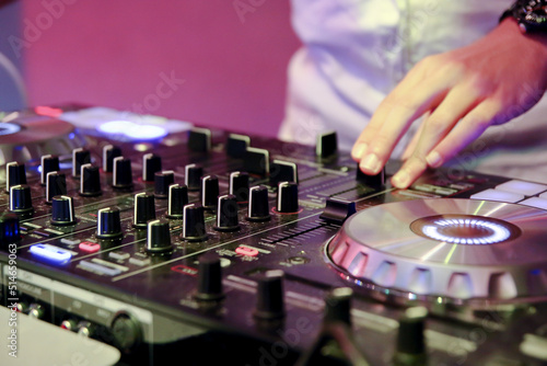 DJ's hand playing music with a mixer console at a party