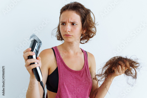 Slika na platnu teenager looks at clipper in amazement, shaving hair on head