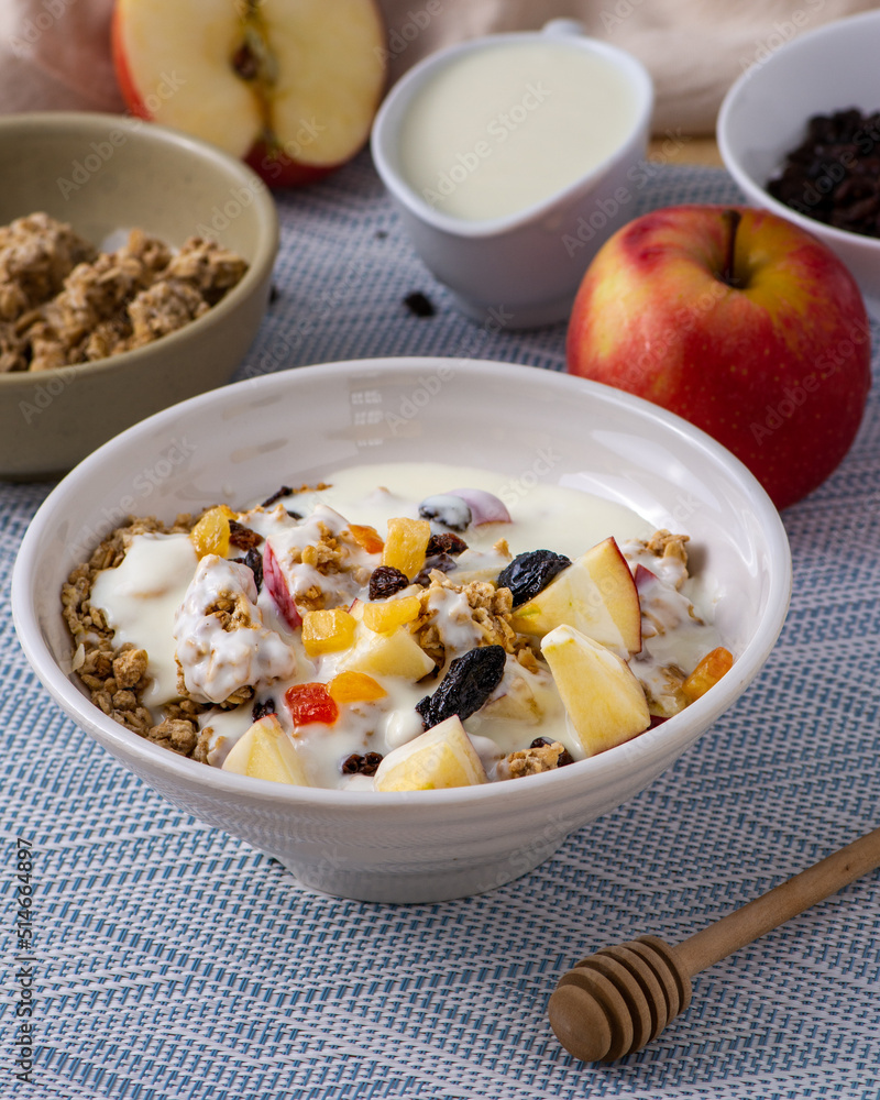 Bowl of Parfait made of granola and fruits surrounded by the ingredients Bowl of Parfait made of granola and fruits surrounded by the ingredients