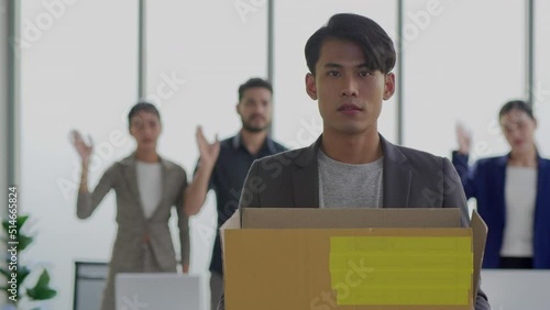 Portrait of jobless asian male emloyee fired from work. Upset young man with box full of things in hands looking at camera. Indoors. Firing from job. Crisis and business photo