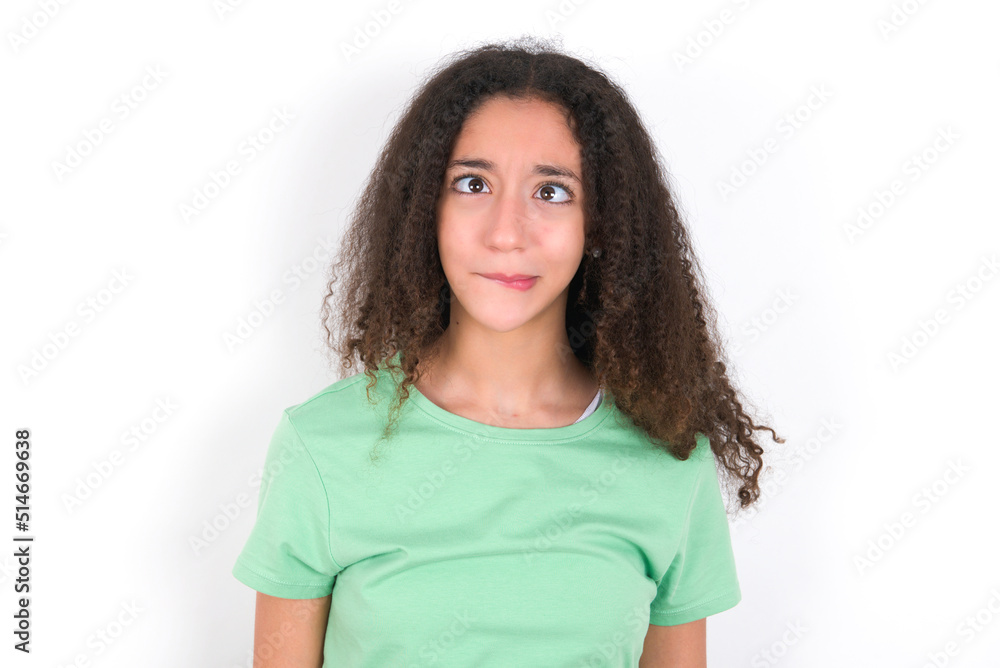 Teenager girl with afro hairstyle wearing green T-shirt over white wall making grimace and crazy face, screaming out of control, funny lunatic expressing freedom and wild. Teenager girl with afro hairstyle wearing green T-shirt over white wall making grimace and crazy face, screaming out of control, funny lunatic expressing freedom and wild.