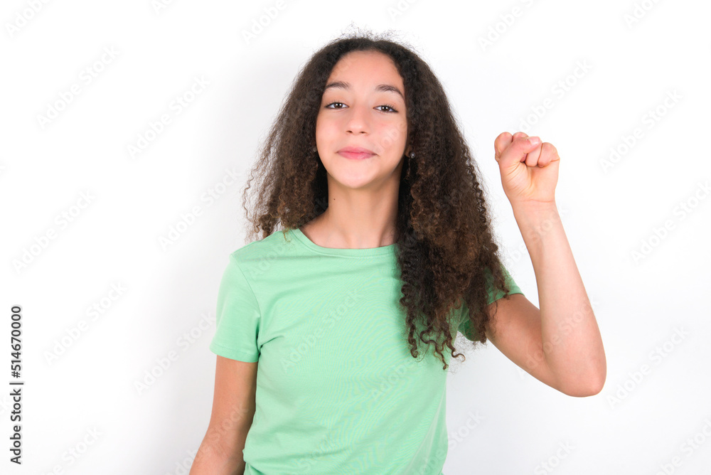 Teenager girl with afro hairstyle wearing green T-shirt over white wall pointing up with fingers number ten in Chinese sign language Shi Teenager girl with afro hairstyle wearing green T-shirt over white wall pointing up with fingers number ten in Chinese sign language Shi