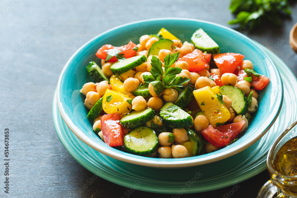 Chickpea salad with tomatoes, cucumber, parsley, onions in a plate, selective focus. Healthy vegetarian food, oriental and Mediterranean cuisine. Chick peas salad