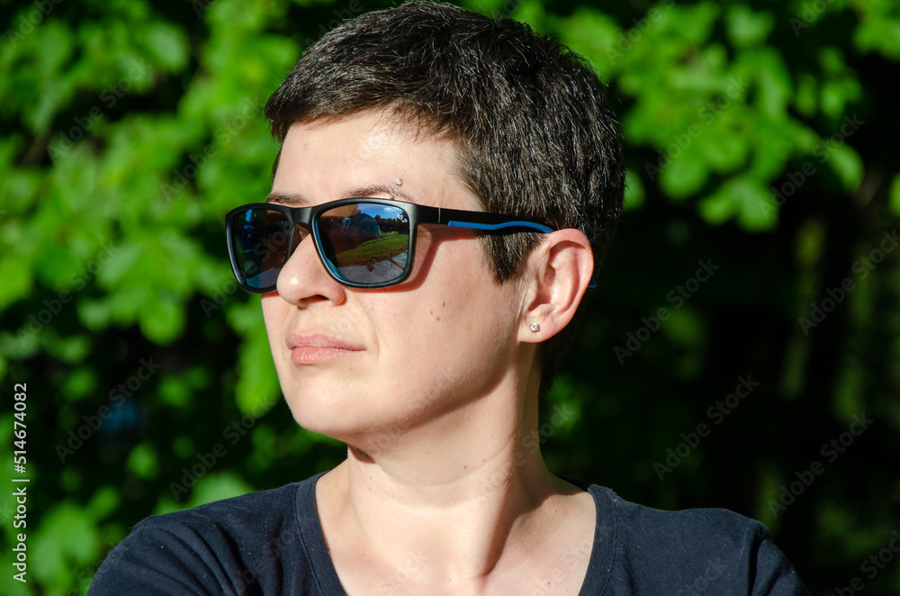 Portrait of a stylish young woman in profile on a summer day on a green natural background. Close-up of a woman's face with sunglasses. Space for text Portrait of a stylish young woman in profile on a summer day on a green natural background. Close-up of a woman's face with sunglasses. Space for text