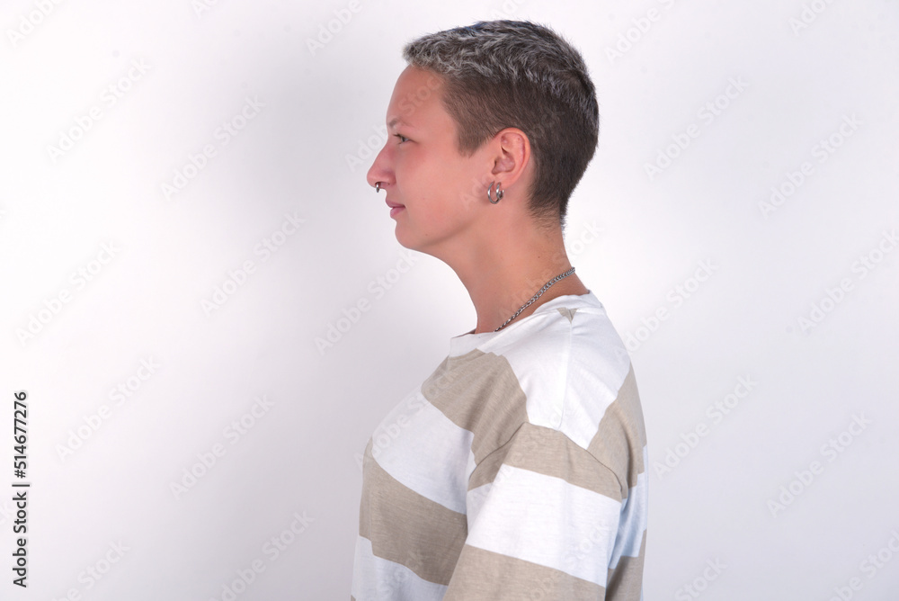 Side view of young happy smiling young woman with short hair wearing striped t-shirt over white background Side view of young happy smiling young woman with short hair wearing striped t-shirt over white background