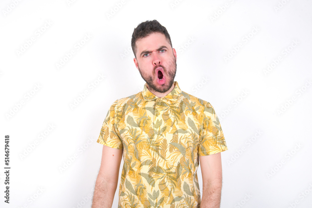 Expressive facial expressions. Shocked stupefied Young caucasian man wearing Hawaiian t-shirt over white background , keeps jaw dropped feels stunned from what he sees aside. Expressive facial expressions. Shocked stupefied Young caucasian man wearing Hawaiian t-shirt over white background , keeps jaw dropped feels stunned from what he sees aside.
