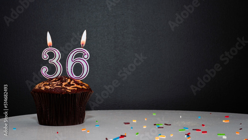 Muffin on black with a number from a candle number 36. Copy space, a pie on a black background, a card for congratulations on your birthday, anniversary. photo