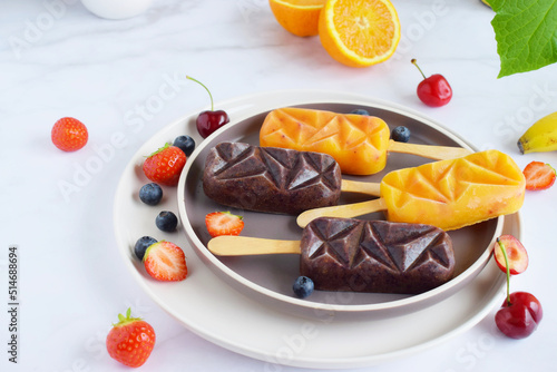 Self made popsicle with fruit pieces in it on a marble background