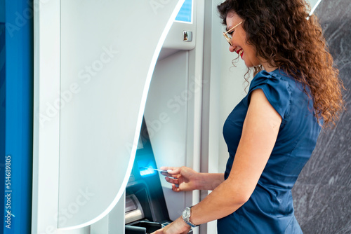 Positive young woman withdrawing cash from the atm 