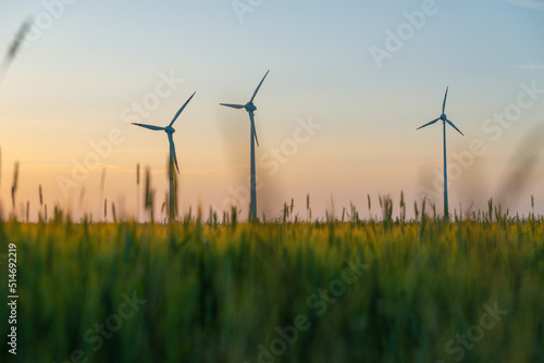 View of wind power turbines, part of a wind farm. Wind turbines on green field in countryside. Wind power plant.