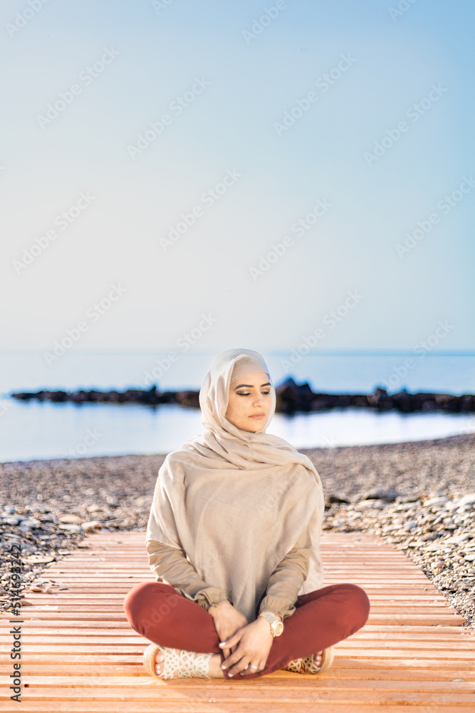 Muslim and modern woman sitting on the beach