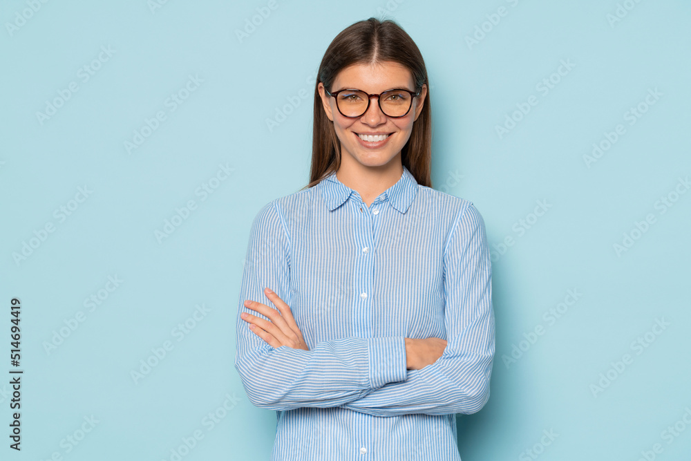 Half length of confident millennial businesswoman in spectacles with crossed arms isolated on blue Half length of confident millennial businesswoman in spectacles with crossed arms isolated on blue