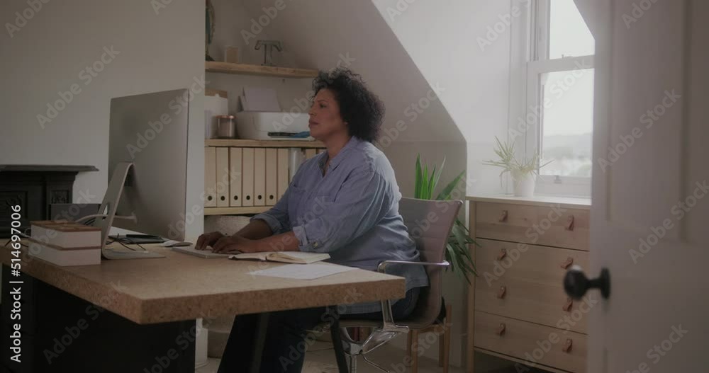 Mature Female Working from Home on Computer in Domestic Room Mature Female Working from Home on Computer in Domestic Room