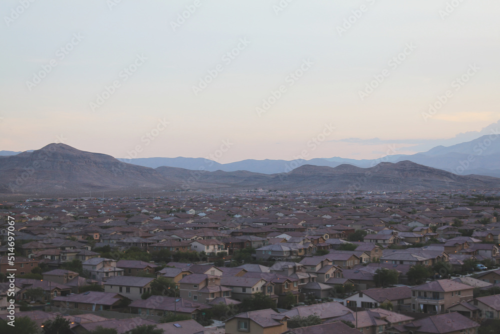 Zoomed out panoramic view of master planned community consisting of single family homes in a major metropolitan city suburb within the desert southwest after sunset with mountains and colorful sky