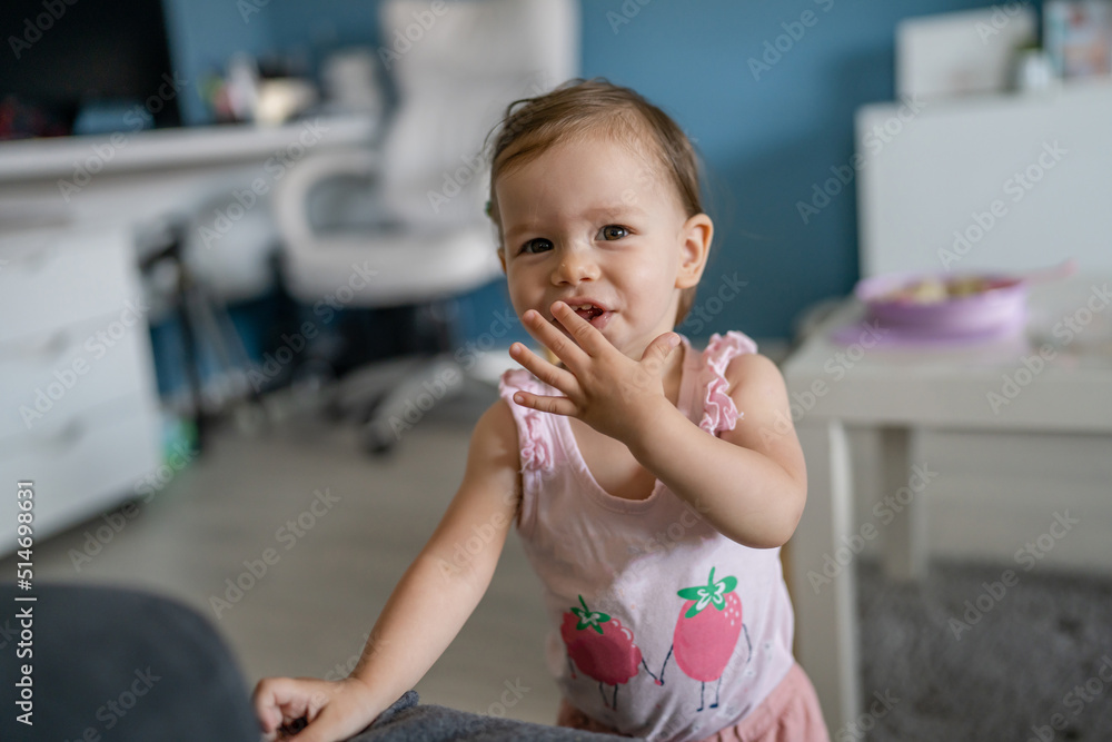 One toddler caucasian full mouth eating with hands at home in the living room front view Early child development learning and playing concept