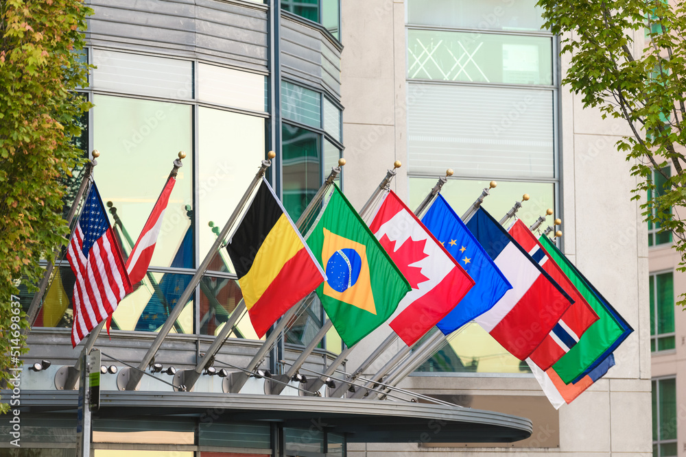 Naklejka premium Row of world flags from global nationas hanging from short flag poles on a building 