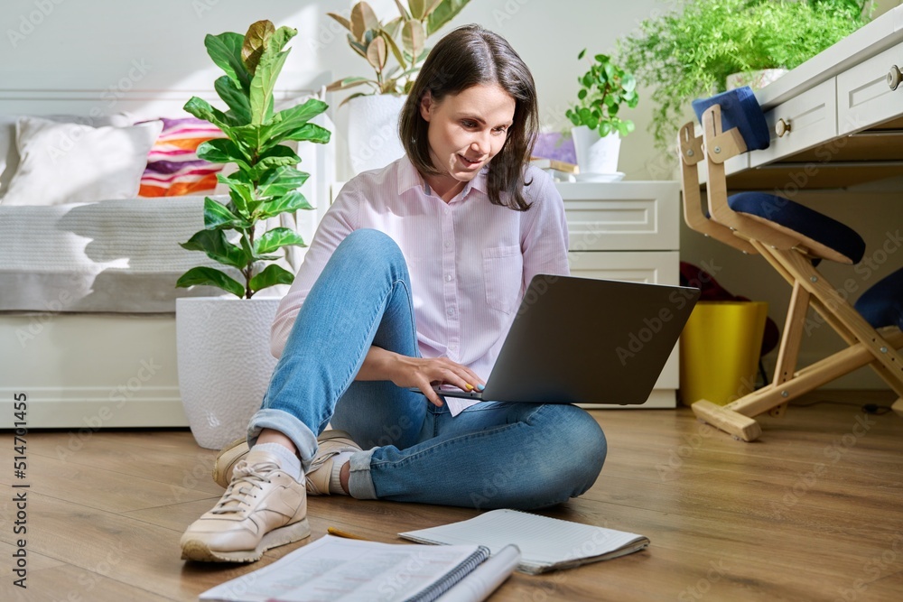 Young female university student studying at home sitting on floor using laptop Young female university student studying at home sitting on floor using laptop