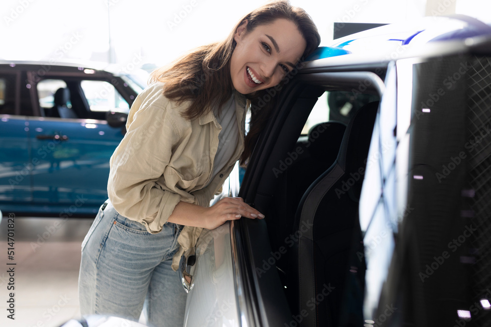 young woman next to a new car in a car dealership