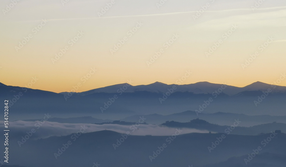 Un mare di nebbia e nuvole al tramonto riempie le valli ai piedii dei monti appennini