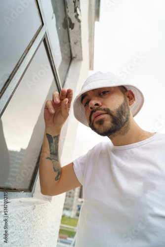 portrait of a latin young man with a beard wears a white t-shirt and cap, outdoor lifestyle and fashion, accessory