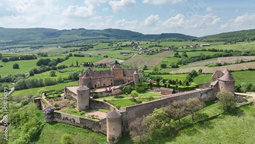Aerial panning shot of Berze le chatel feudal medieval castle with double enclosure of walls, round towers, donjon, fortified gatehouse on a hill in Central France photo