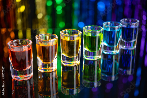 Rainbow drink. Glass shot of alcohol liquor. Bar counter. Rainbow colors. Colored vodka. LGBT Pride. Rainbow flag, symbol gays and lesbians LGBT, LGBTQ. Good for Party. Rainbow on black background.