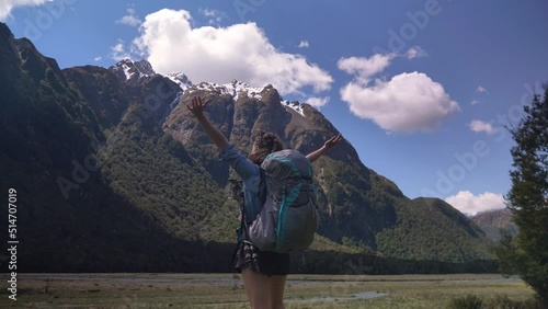 Slider, female hiker stretches in mountainous valley, Routeburn Track New Zealand photo