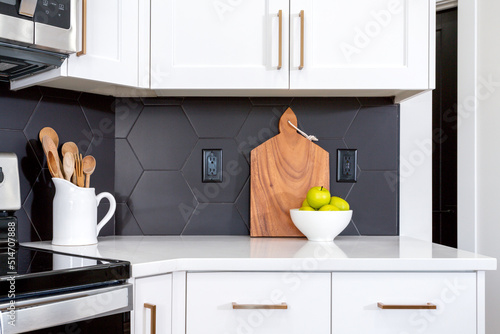 Vászonkép A modern farmhouse kitchen with white cabinets, black hexagon tile backsplash and and gold pulls