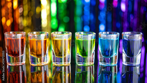 Rainbow drink. Glass shot of alcohol liquor. Bar counter. Rainbow colors. Colored vodka. LGBT Pride. Rainbow flag, symbol gays and lesbians LGBT, LGBTQ. Good for Party. Rainbow on black background.