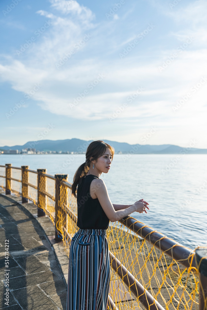 夕暮れの海を散策する女性