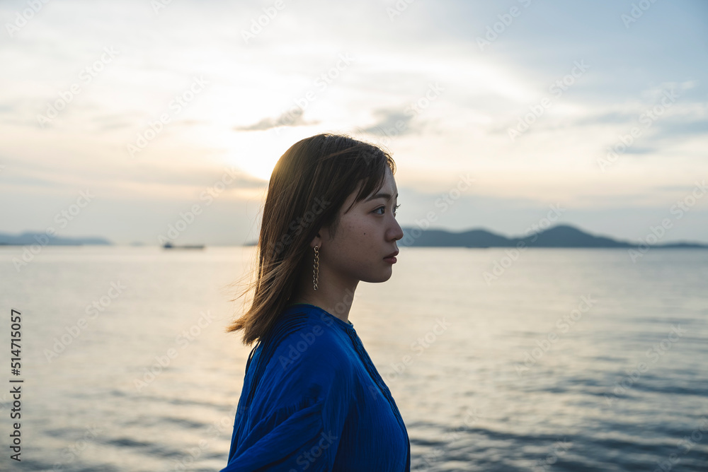 夕暮れの海にいる青いワンピースの女性 夕暮れの海にいる青いワンピースの女性